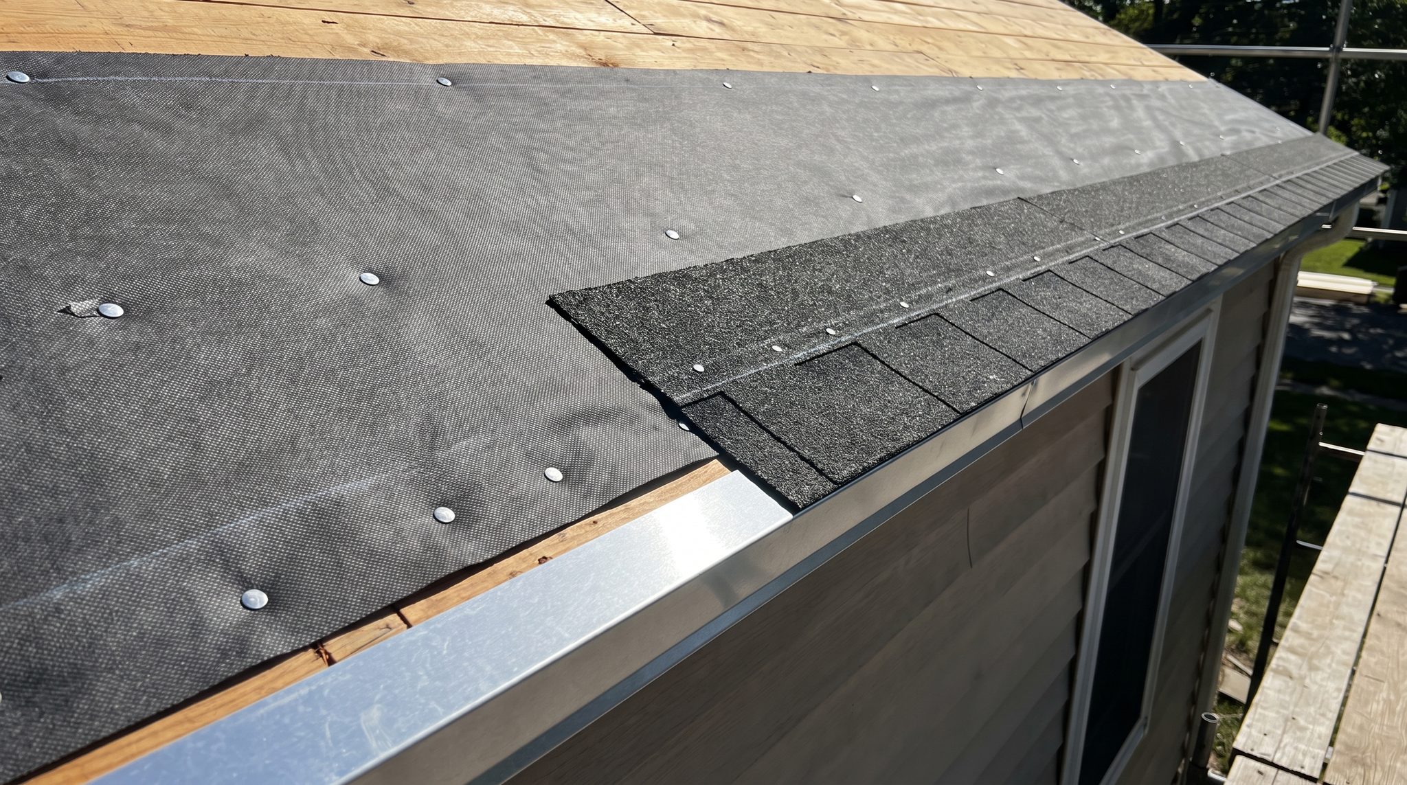 Exposed plywood roof deck with self-adhered underlayment being rolled out before new shingles